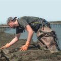 Werknemer met het Hapo exoskelet, in actie op een werklocatie, leunt voorover om werk met de handen uit te voeren, waarbij rugondersteuning wordt geboden